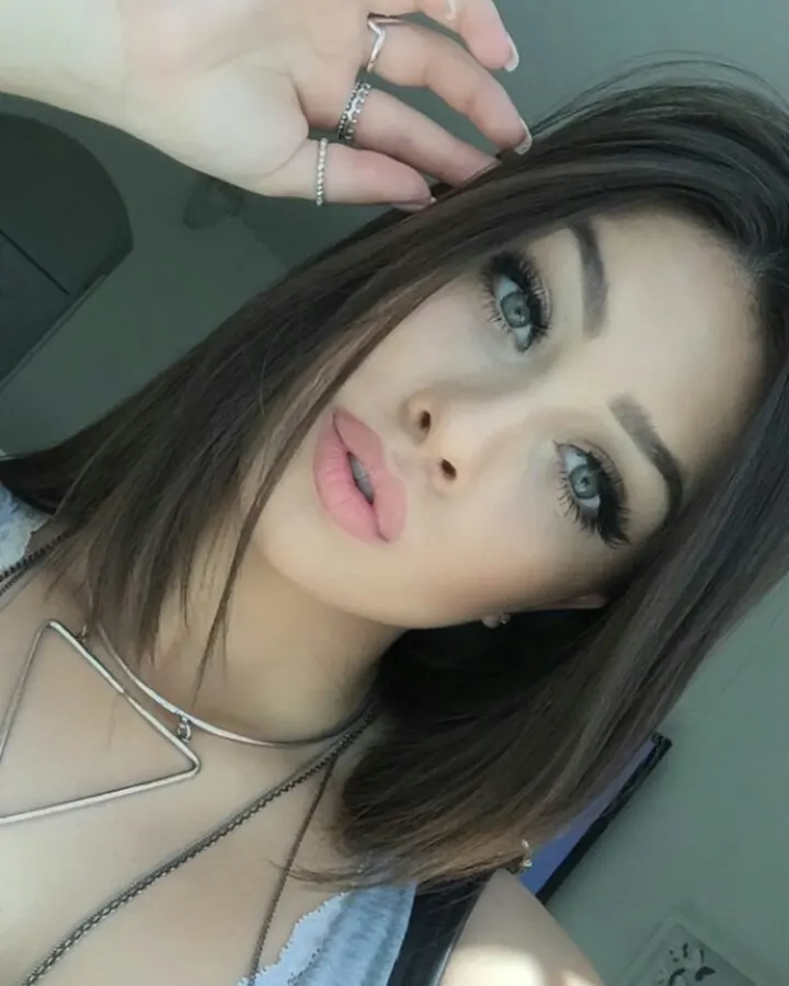 Jeune femme brune, gros plan selfie, collier triangle, regard vers l'objectif