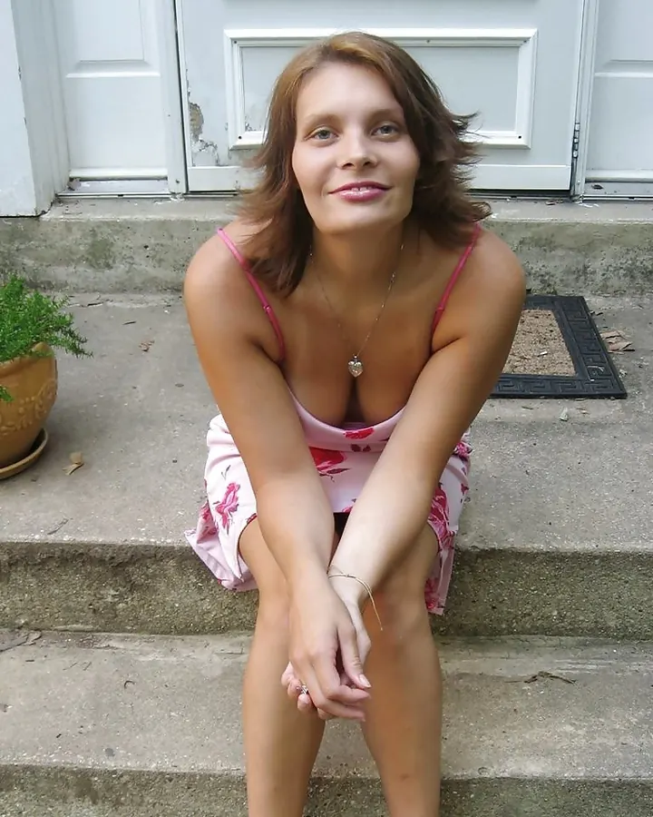 Femme assise sur des marches, robe rose fleurie, regard calme